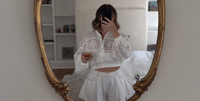 Consumer wearing white clothes and staring at themselves in the mirror to identify their body type