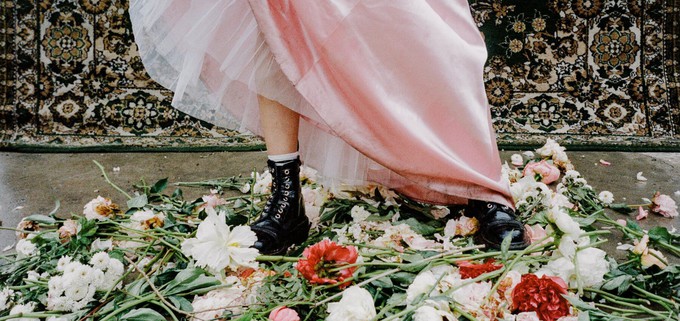 consumer in a long dress and boots next to flowers to show we can fight climate change with our wardrobes