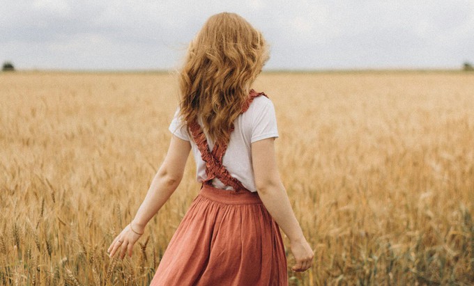 Woman running next to a field and wearing a cottagecore fashion aesthetic outfit